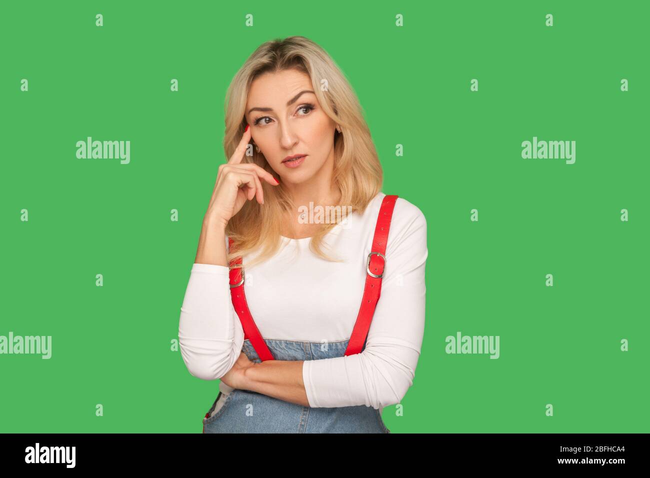 Penchons-nous ! Portrait d'une femme adulte pensive intelligente dans des combinaisons élégantes touchant le temple tout en pensant intensément, en utilisant et en méditant une solution intelligente. Banque D'Images