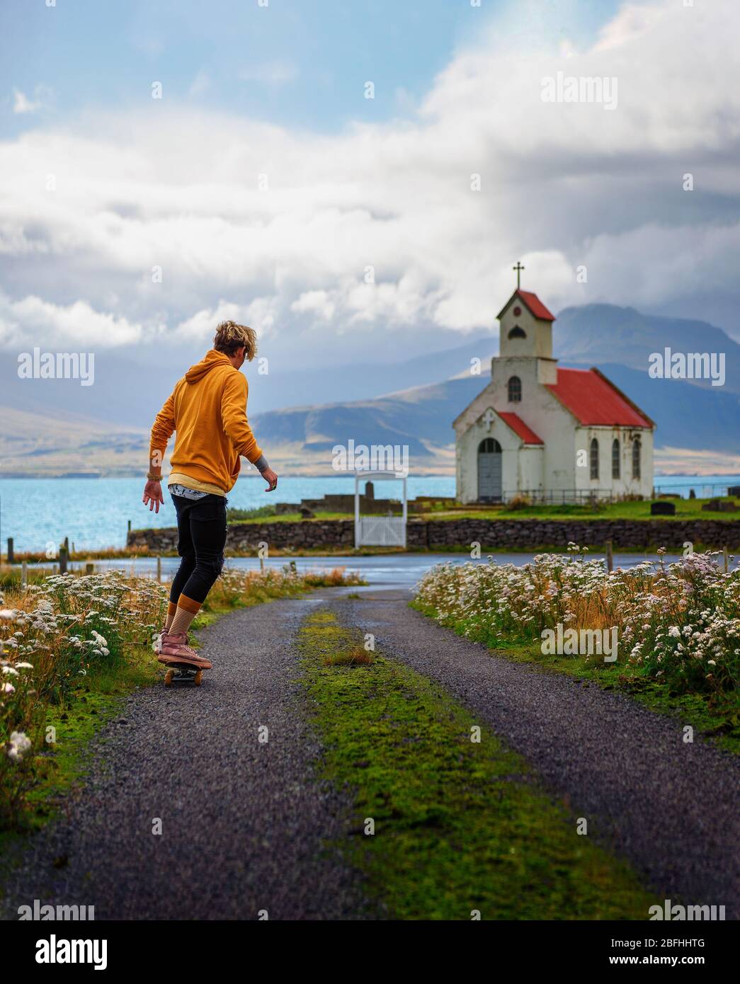 Jeunes patineurs à roulettes vers une église et un cimetière en Islande Banque D'Images