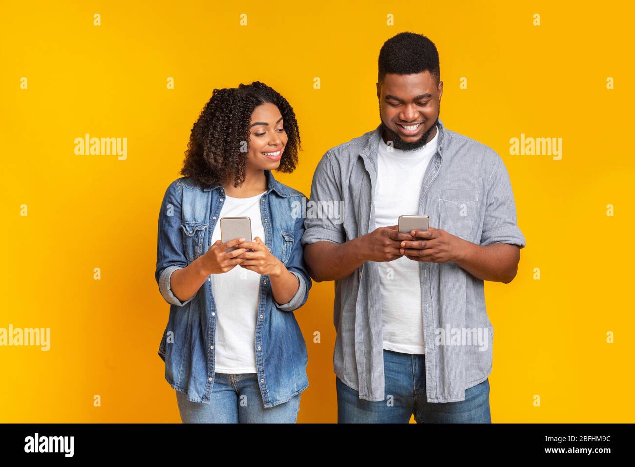 Curieuse petite amie noire qui s'épluche dans le smartphone de mon ami, essayant de lire des messages Banque D'Images