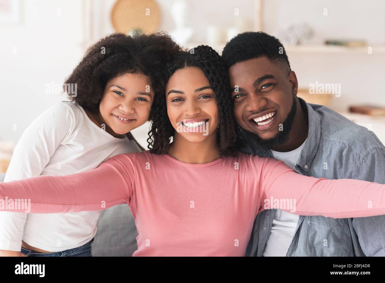 Une femme noire positive prenant Selfie avec son mari et sa fille à la maison Banque D'Images