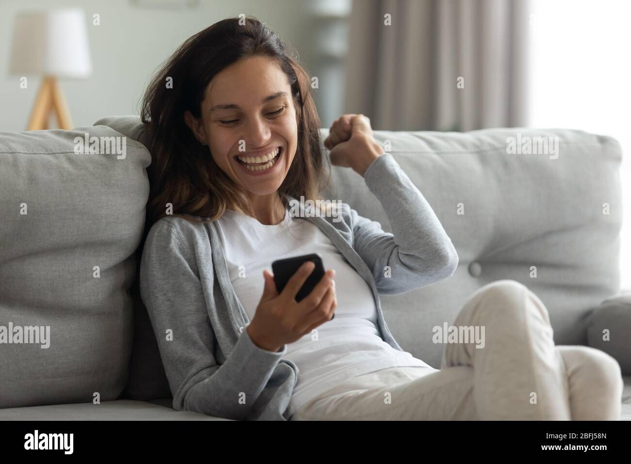 Une femme excitée par téléphone, célébrant la victoire en ligne, un bon message Banque D'Images