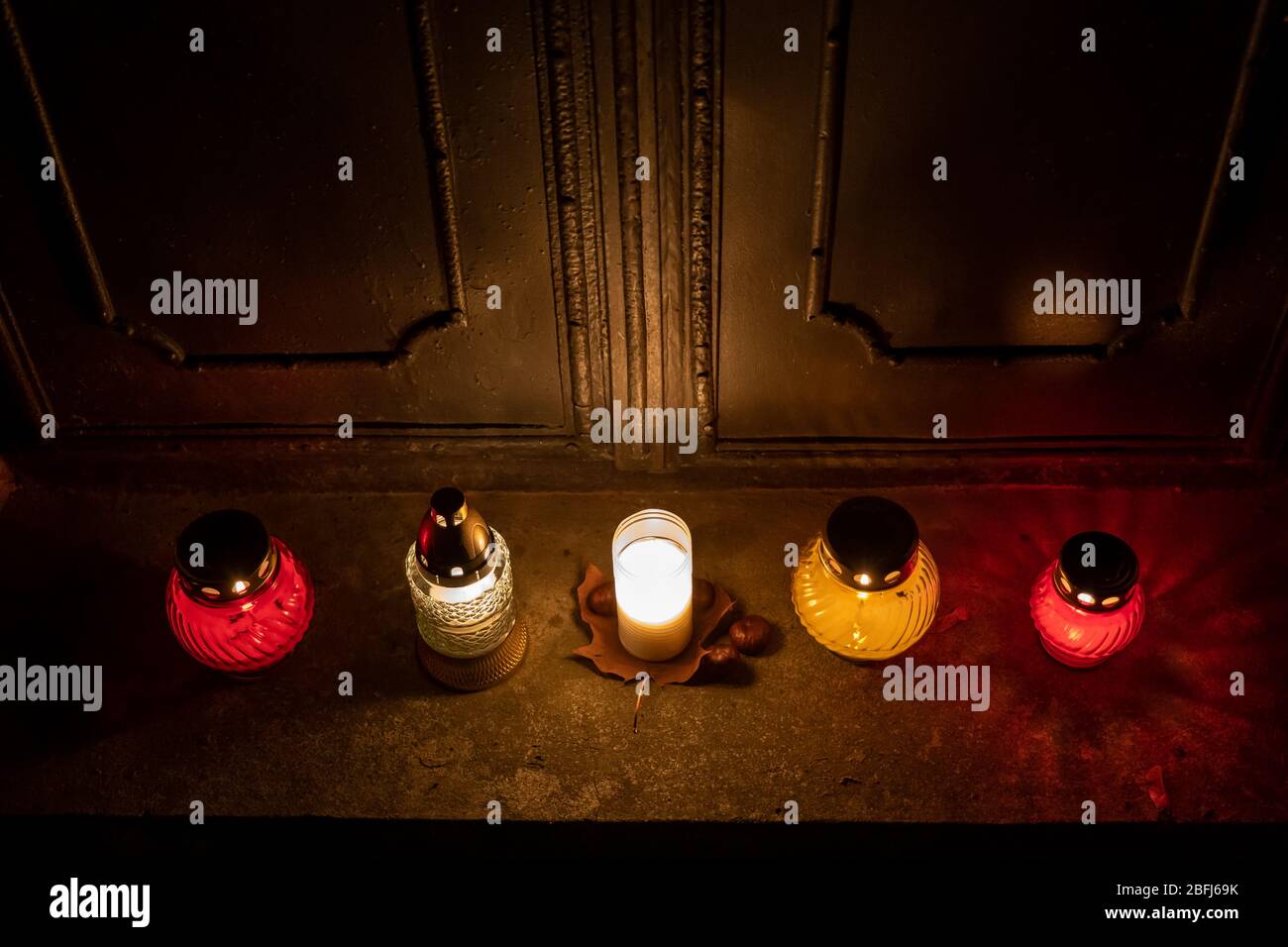 Des bougies tombales s'allument à gauche aux portes d'un vieux tombeau dans un cimetière la nuit, style rétro vintage stylisé Banque D'Images