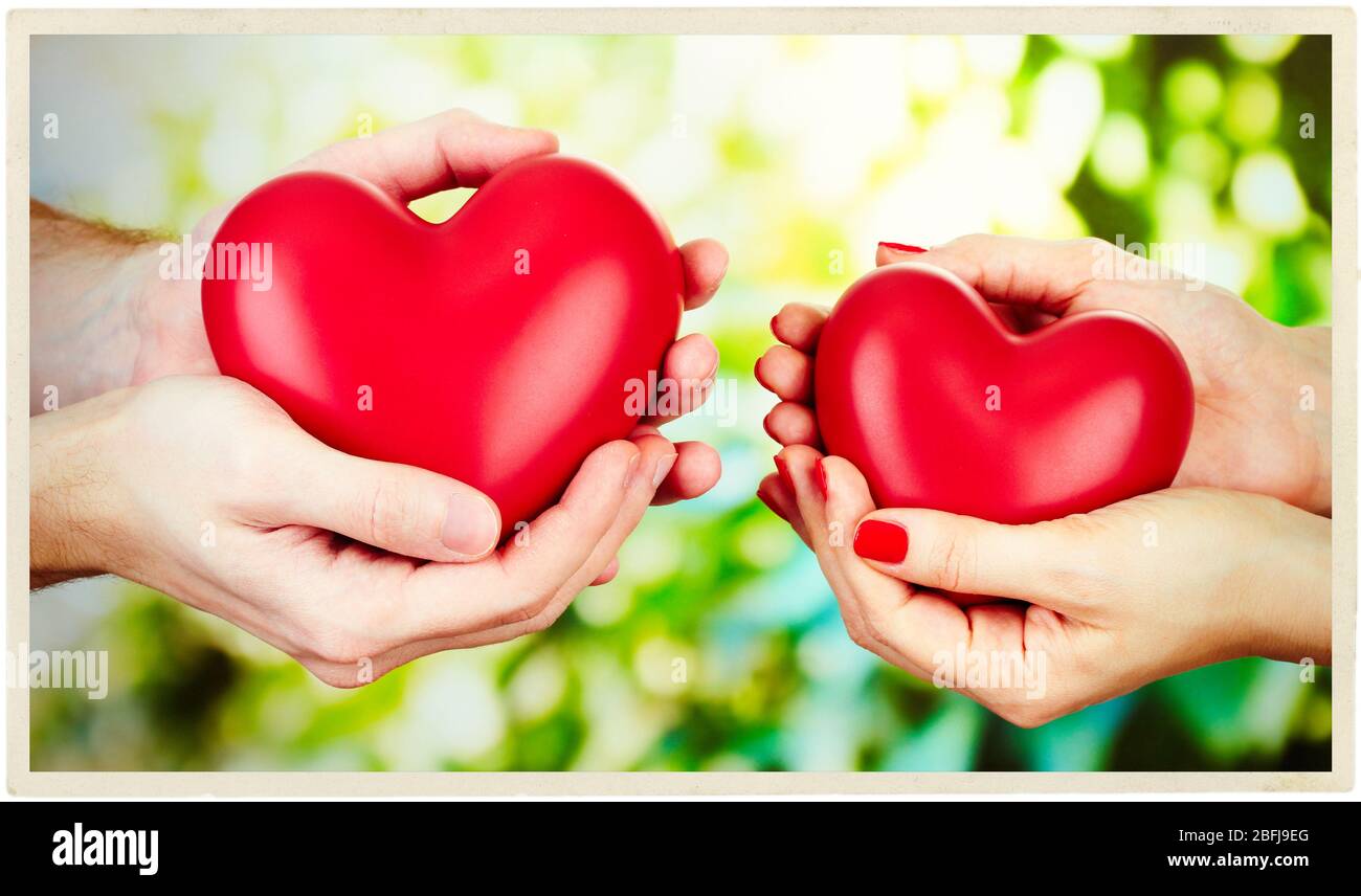 Couple aimant tenant les coeurs dans les mains sur fond ensoleillé de nature Banque D'Images