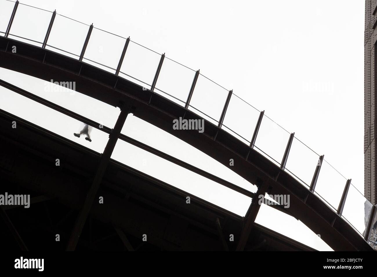 Silhouette d'une personne marchant sur la plateforme transparente au premier étage de la Eiffel, vue du dessous, Paris Banque D'Images