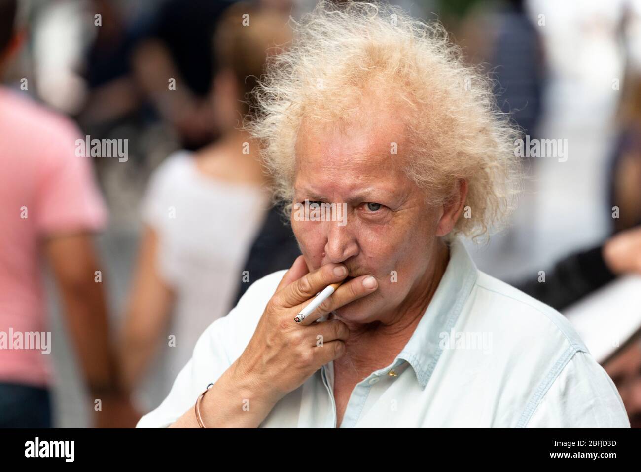 Portrait d'une femme avec des cheveux frisés fume sur le marché des artistes à Montmartre, Paris Banque D'Images