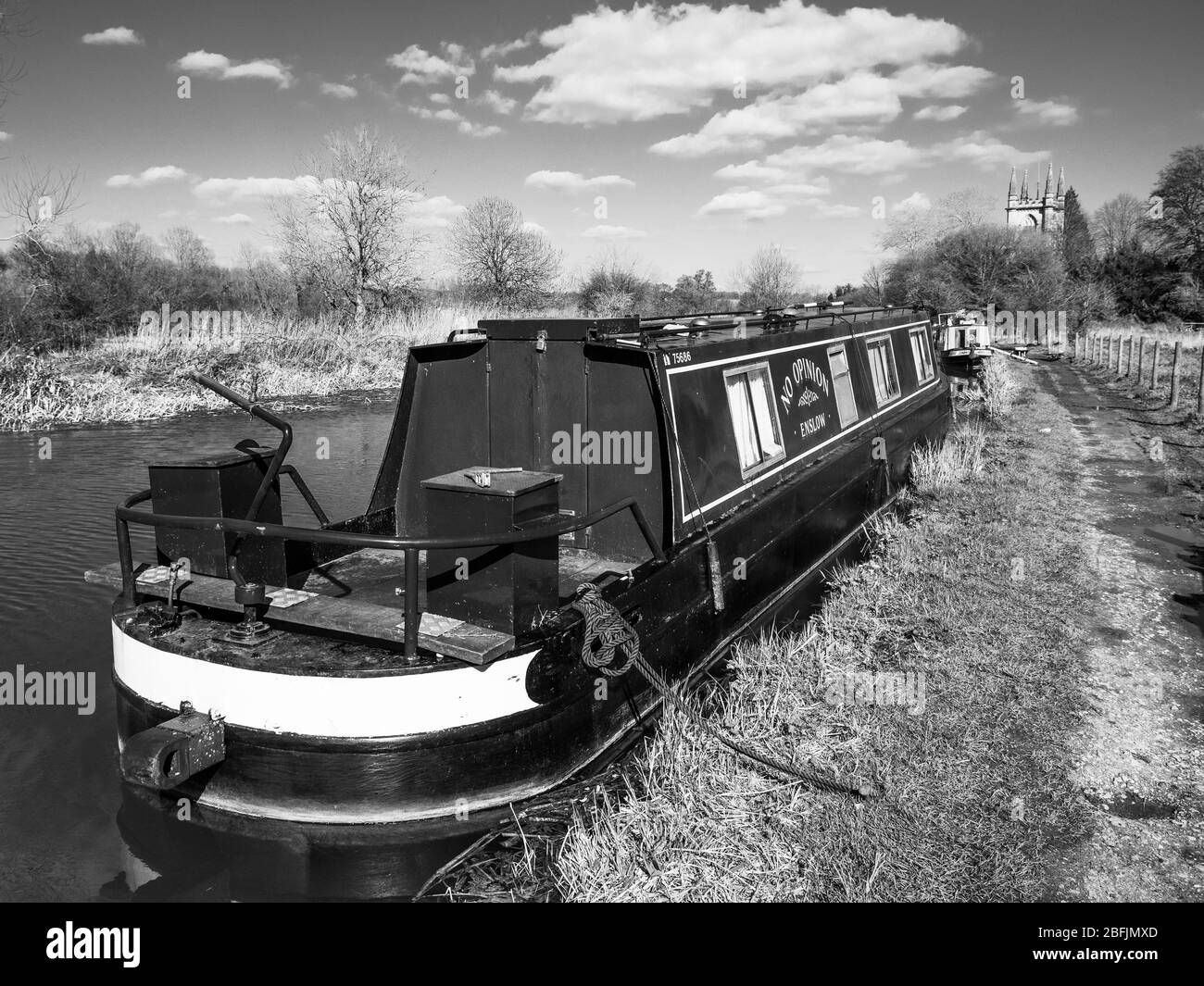 Paysage noir et blanc de la barque sur le canal de Kennet et Avon, avec l'église Saint-Laurent, Hungerford, Berkshire, Angleterre, Royaume-Uni, GB. Banque D'Images