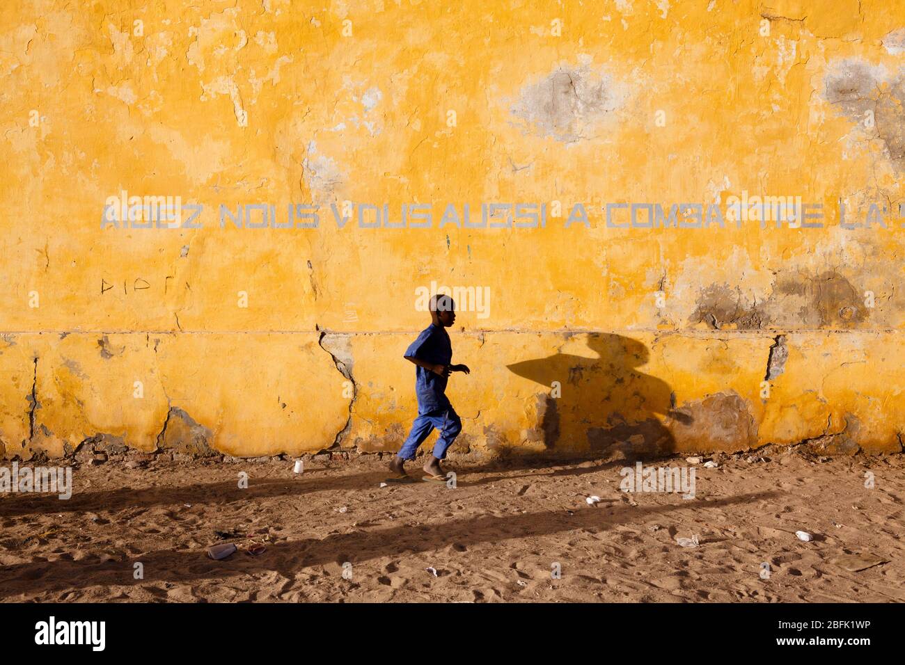 Le jeune garçon traverse le vieux quartier de Saint Louis, au Sénégal. Banque D'Images