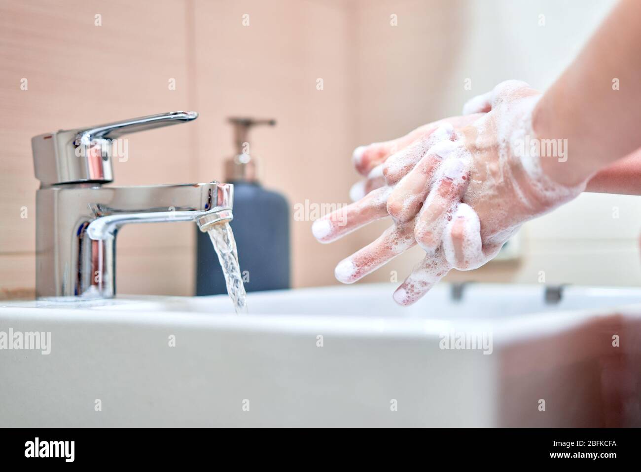 Lavage des mains avec du savon sous l'eau dans la salle de bains Banque D'Images