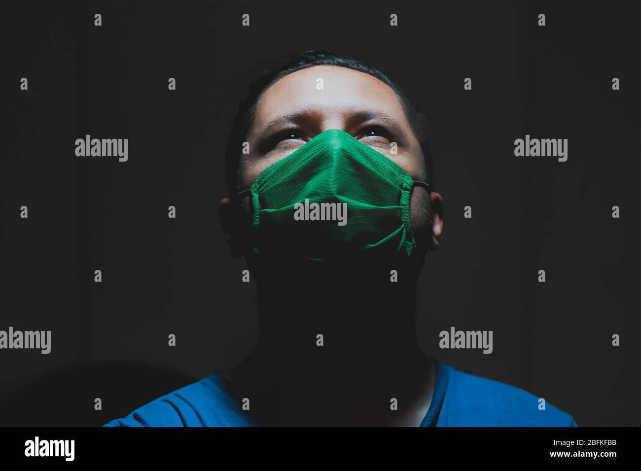 Le jeune homme blanc porte un masque médical vert pendant la quarantaine à sa maison pour empêcher d'obtenir la grippe , le plafonnier, Bogota, 18 avril 2020 Banque D'Images