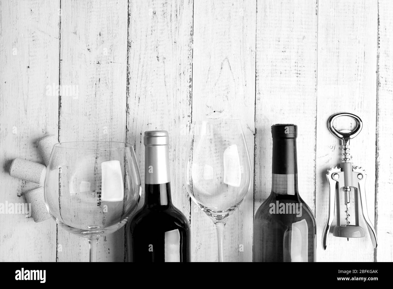 Bouteilles de vin, verre et corkvelle sur table en bois, stylisation rétro noir et blanc Banque D'Images
