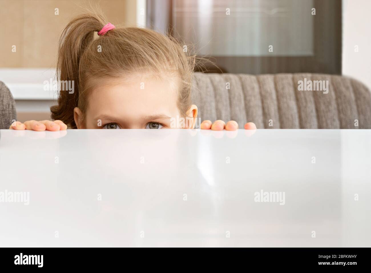 Petite fille Peeking de derrière la table, espace de copie Banque D'Images