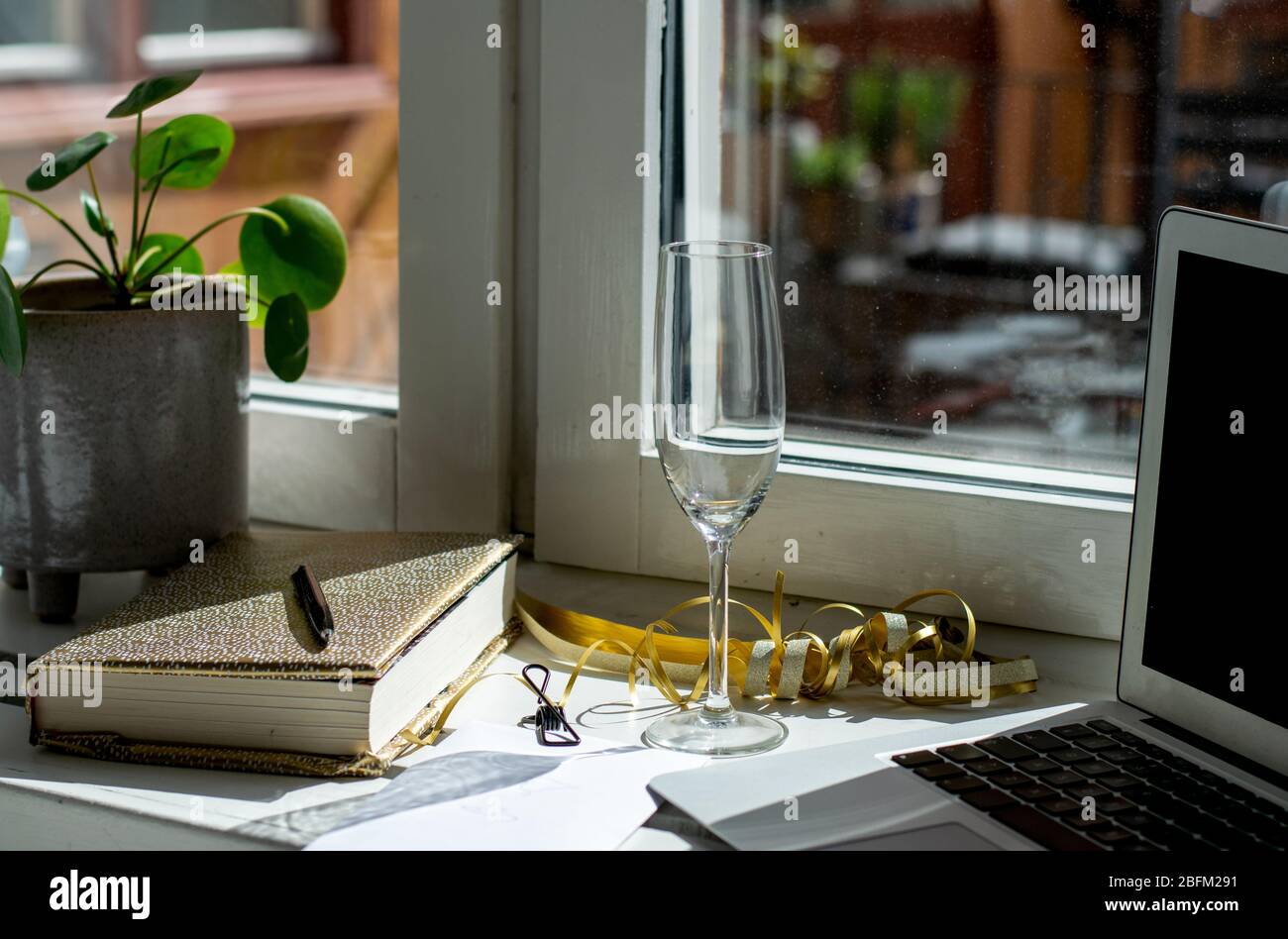 Préparations de célébration avec carnet doré, verre à champagne vide au stylo, appareil photo et clip pour reliure sur enveloppe blanche Banque D'Images