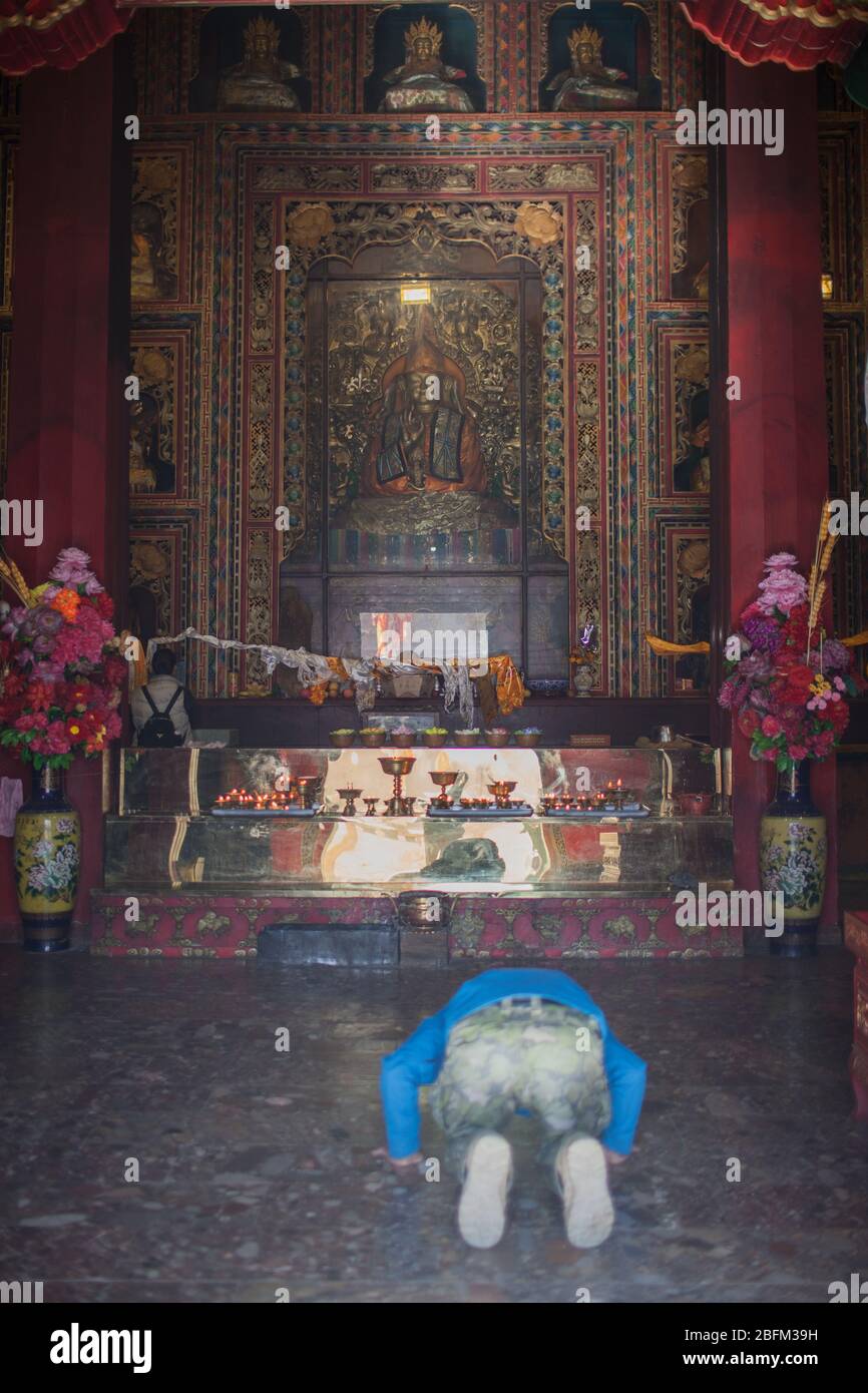 Un homme s'agenouillant avant le bouddha à l'intérieur du temple bouddhiste de Ringa, Shangri la, Chine 2019 Banque D'Images