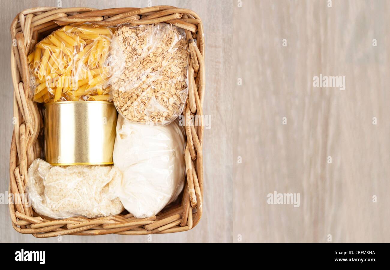 Don livraison de nourriture aide à panier céréales, pâtes, en conserve sur fond blanc en bois naturel. Banque D'Images