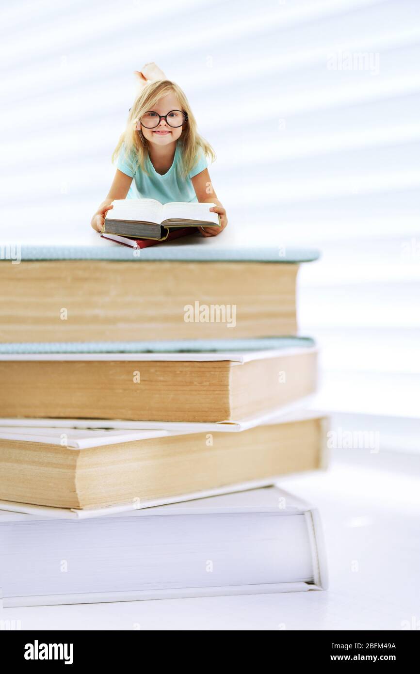 Mignonne petite fille sur la pile de livres isolés sur blanc Banque D'Images