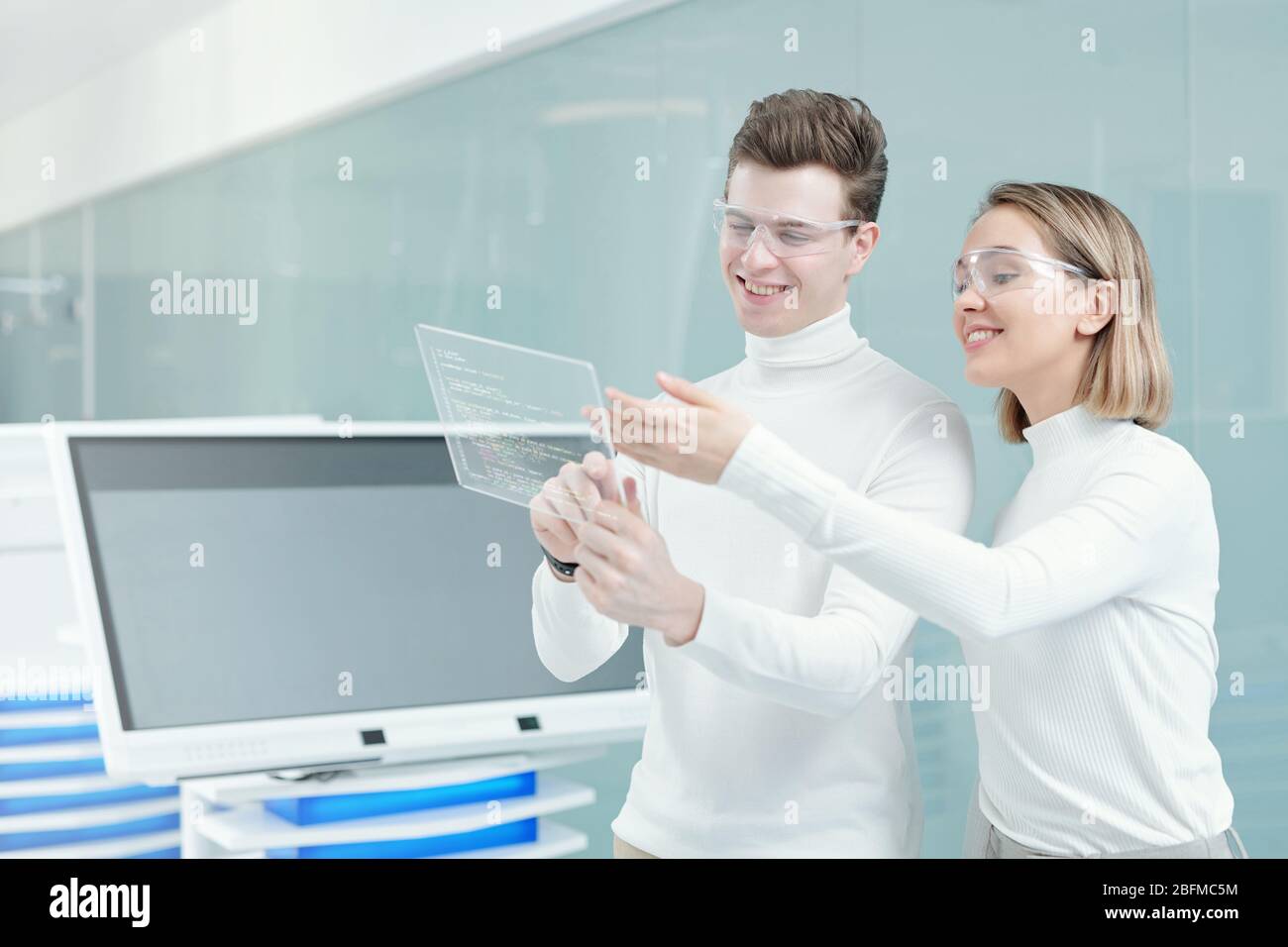 Deux jeunes développeurs de logiciels joyeux préparant la présentation du nouveau programme, tandis que l'un d'eux explique ses principes principaux Banque D'Images