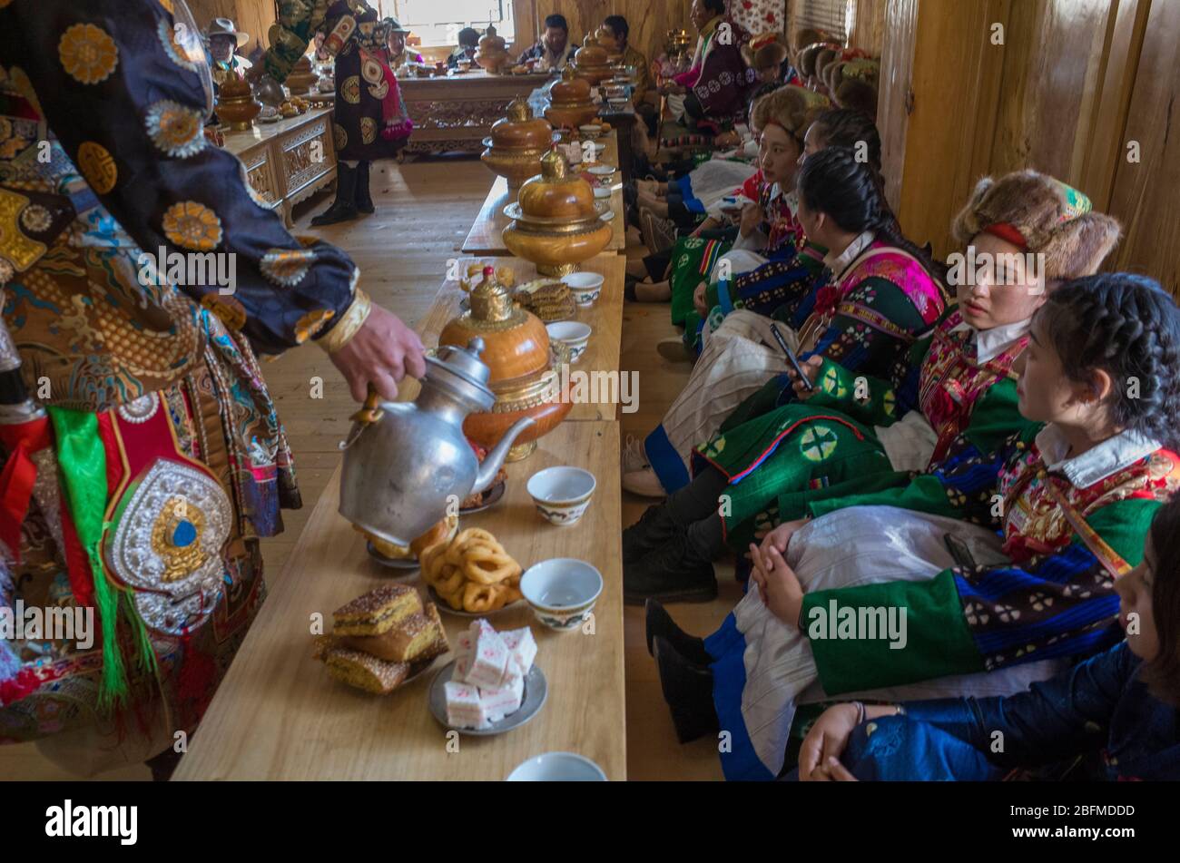 Homme servant de la nourriture aux demoiselles d'honneur lors d'un mariage bouddhiste. Shangri la Chine 2019 Banque D'Images