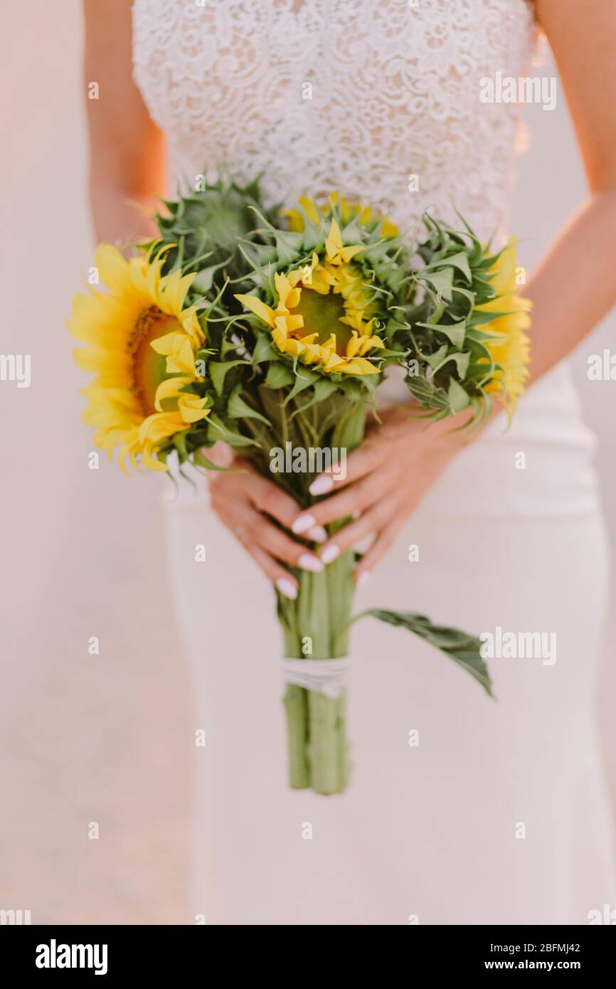 femme tenant bouquet de tournesol au coucher du soleil. photo de mariage de beaux-arts. Bouquet de fleurs de soleil pour mariage. Banque D'Images