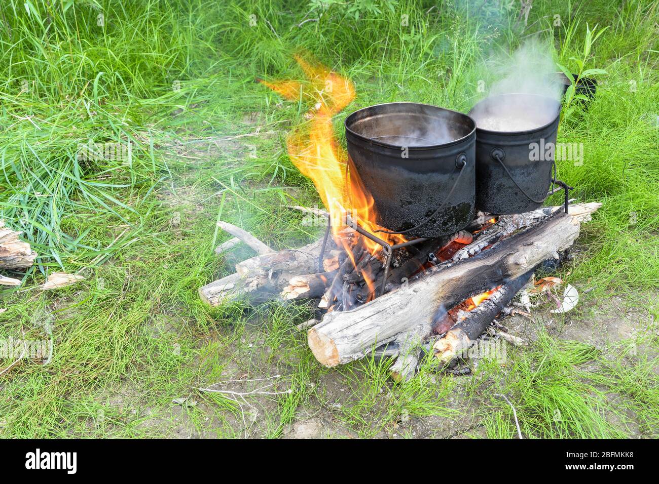 Dîner de cuisine en jeu. Chaudières avec eau bouillante sur un stand au-dessus d'un feu brûlant. Banque D'Images