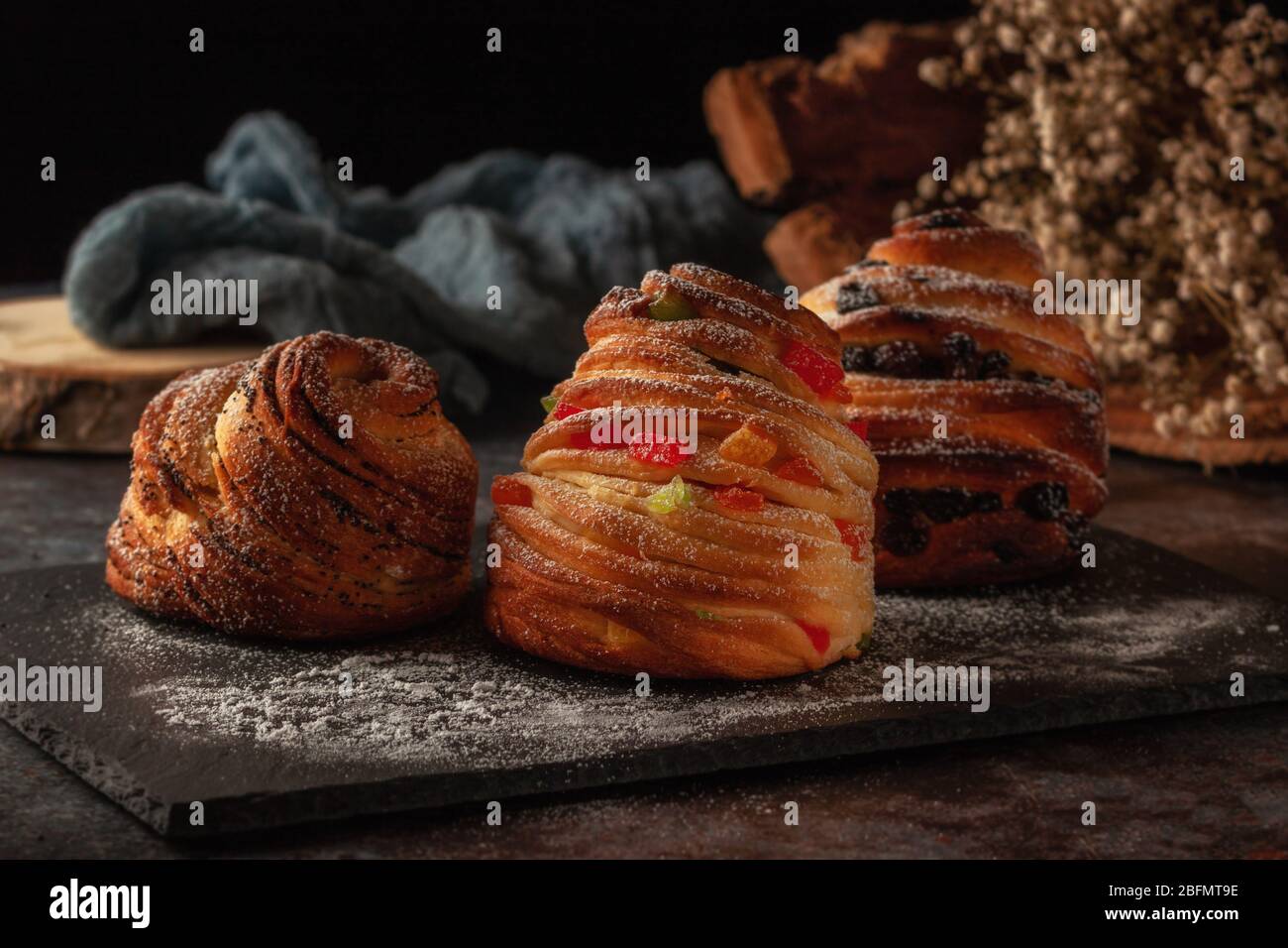 Kraffins aux raisins secs, fruits confits et graines de pavot, arrosés de sucre en poudre. Banque D'Images