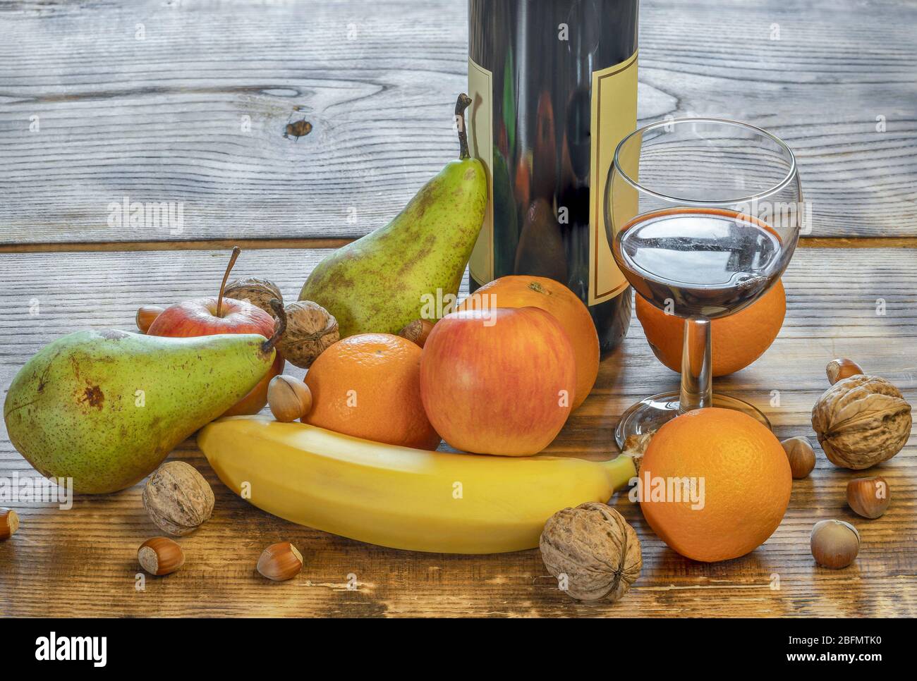 Un verre et une bouteille de vin aux fruits et de fruits mélangés à côté de la table Banque D'Images