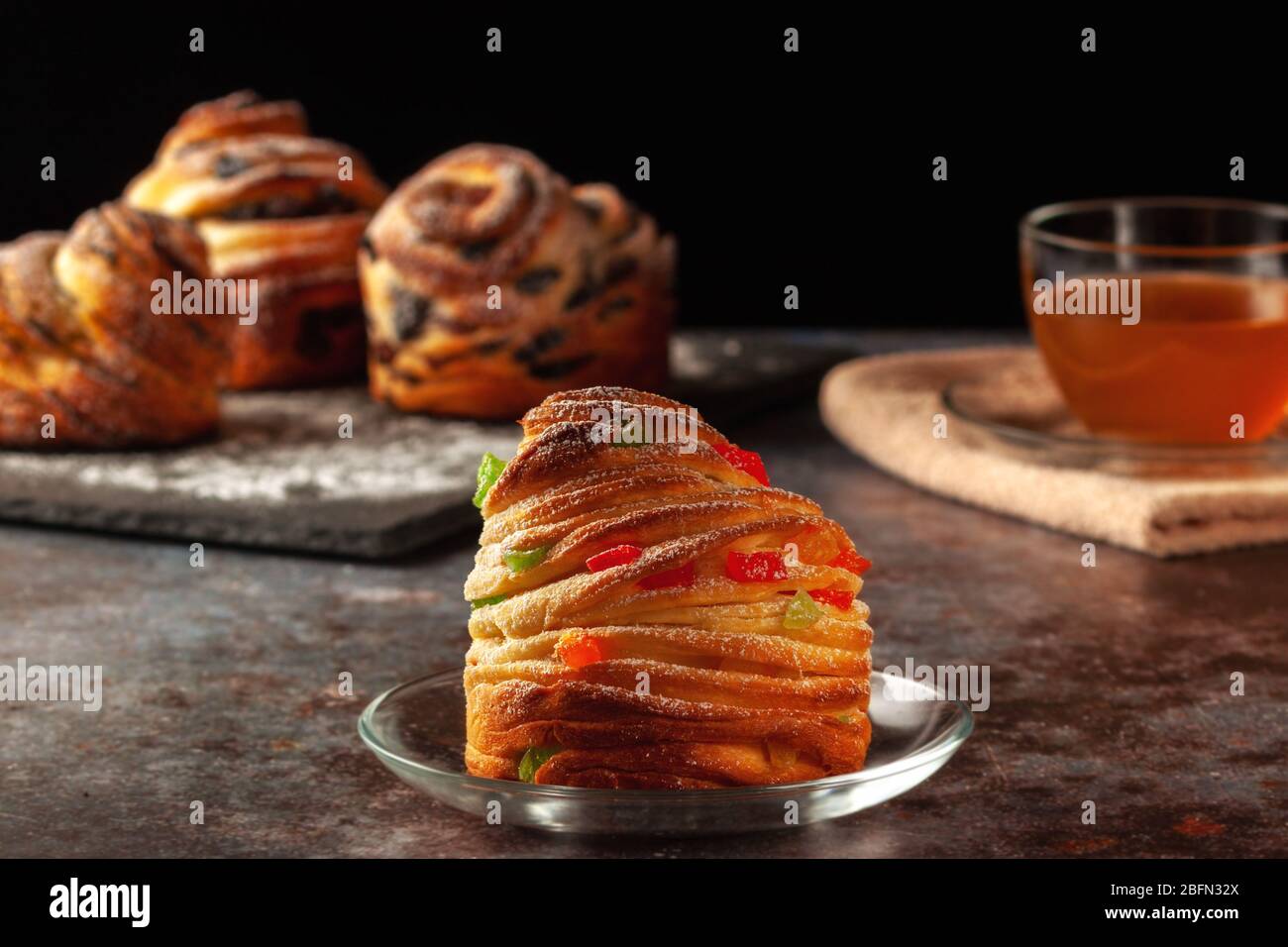 Kraffins aux raisins secs, fruits confits et graines de pavot, arrosés de sucre en poudre. Banque D'Images