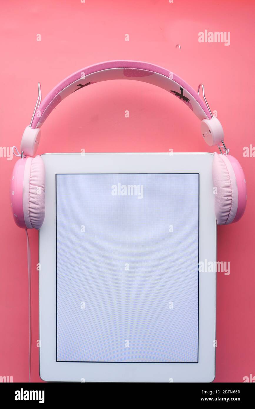 tablette numérique et casque sur fond rose Banque D'Images