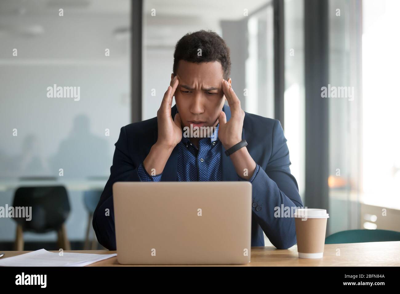 Un homme d'affaires africain assis au bureau tactile temples souffre de maux de tête Banque D'Images