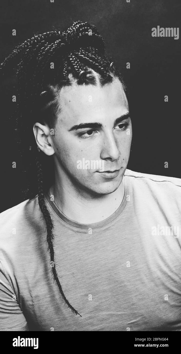 Modèle masculin élégant avec des tresses afro posé en studio sur un arrière-plan isolé. Style, tendances, mode concept. Banque D'Images Modèle masculin élégant avec des tresses afro posé en studio sur un arrière-plan isolé. Style, tendances, mode concept. Banque D'Images
