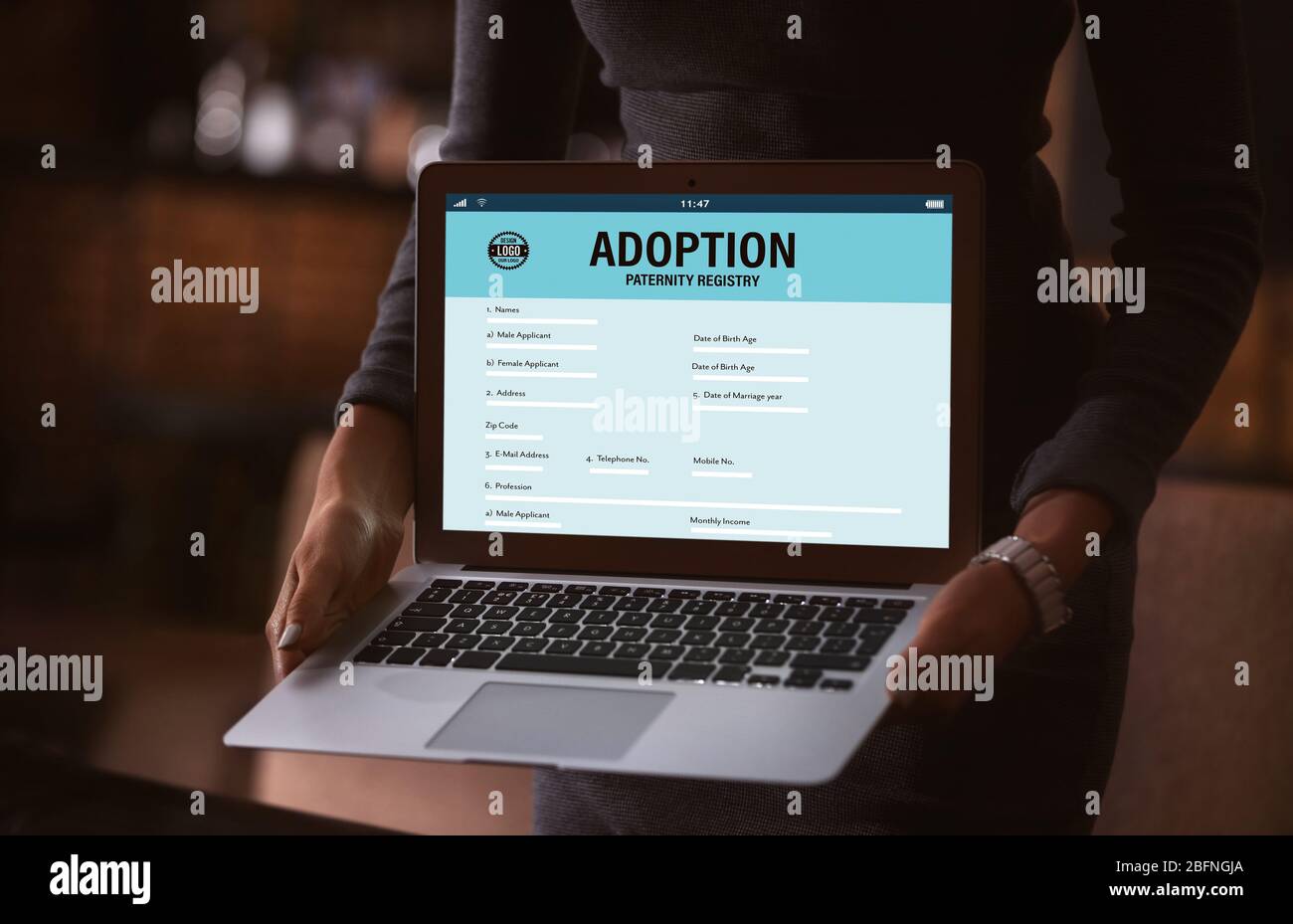Concept d'adoption. Femme tenant un ordinateur portable. Formulaire de paternité à l'écran Banque D'Images