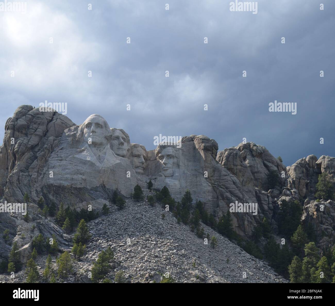 Fin du printemps dans les Black Hills du Dakota du Sud : soleil et ombres sur le monument commémoratif national du Mont Rushmore à l'approche des nuages de tempête Banque D'Images