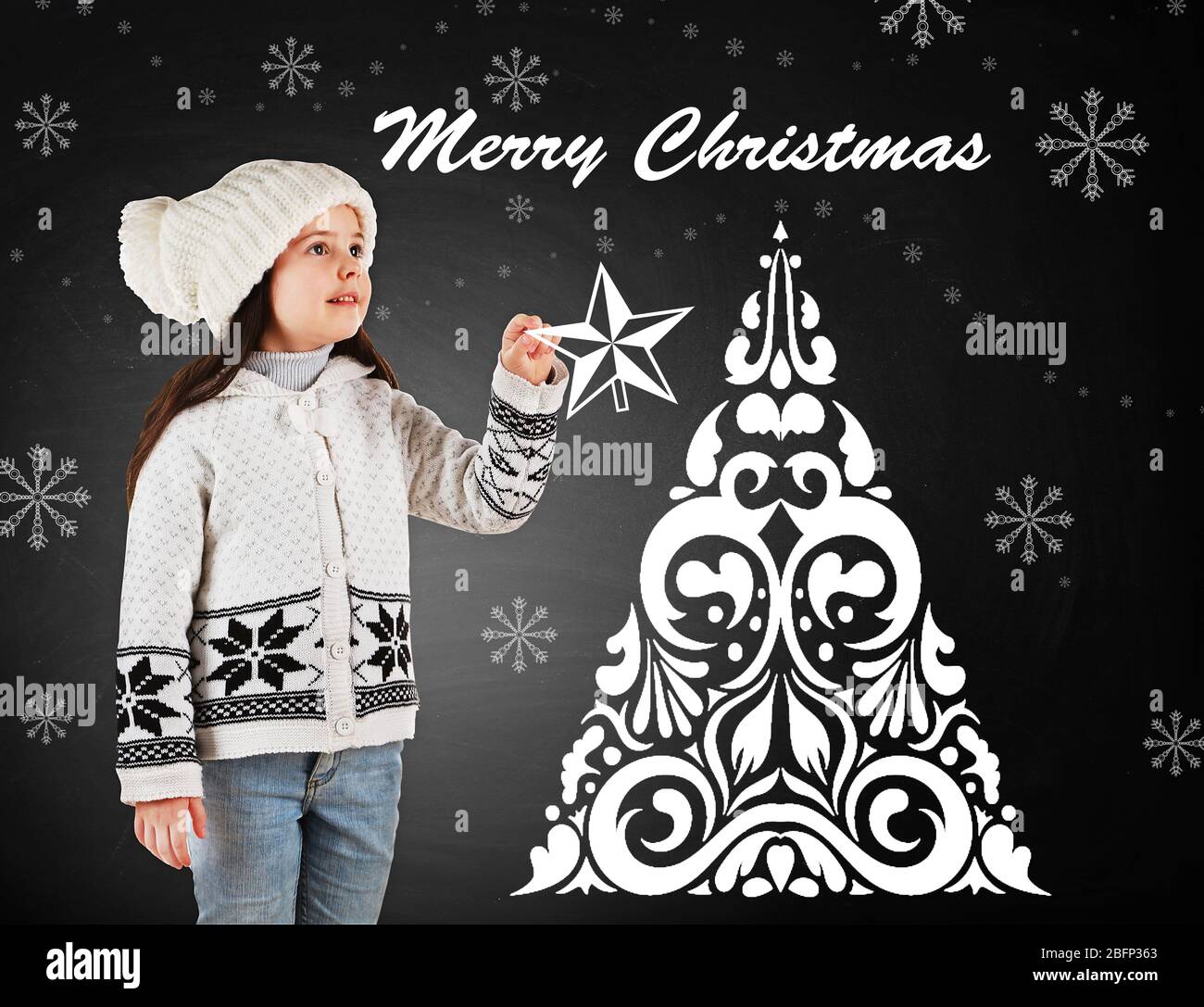 Petite fille dans un tricot à la mode et arbre de Noël dessiné sur fond de tableau noir Banque D'Images