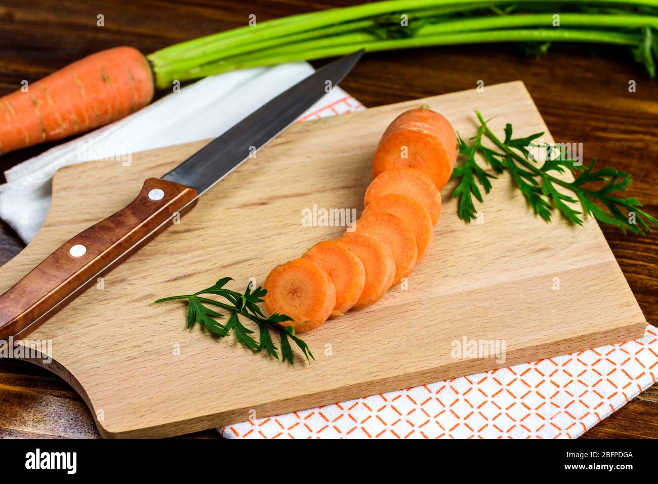 Carottes et couteaux frais tranchés sur un tableau de découpe. Mise au point sélective. Banque D'Images