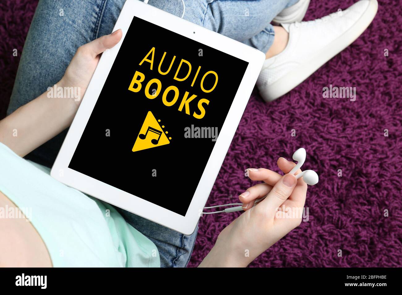 Concept de livres audio et de technologie moderne. Femme utilisant une tablette et des écouteurs, près de chez elle Banque D'Images