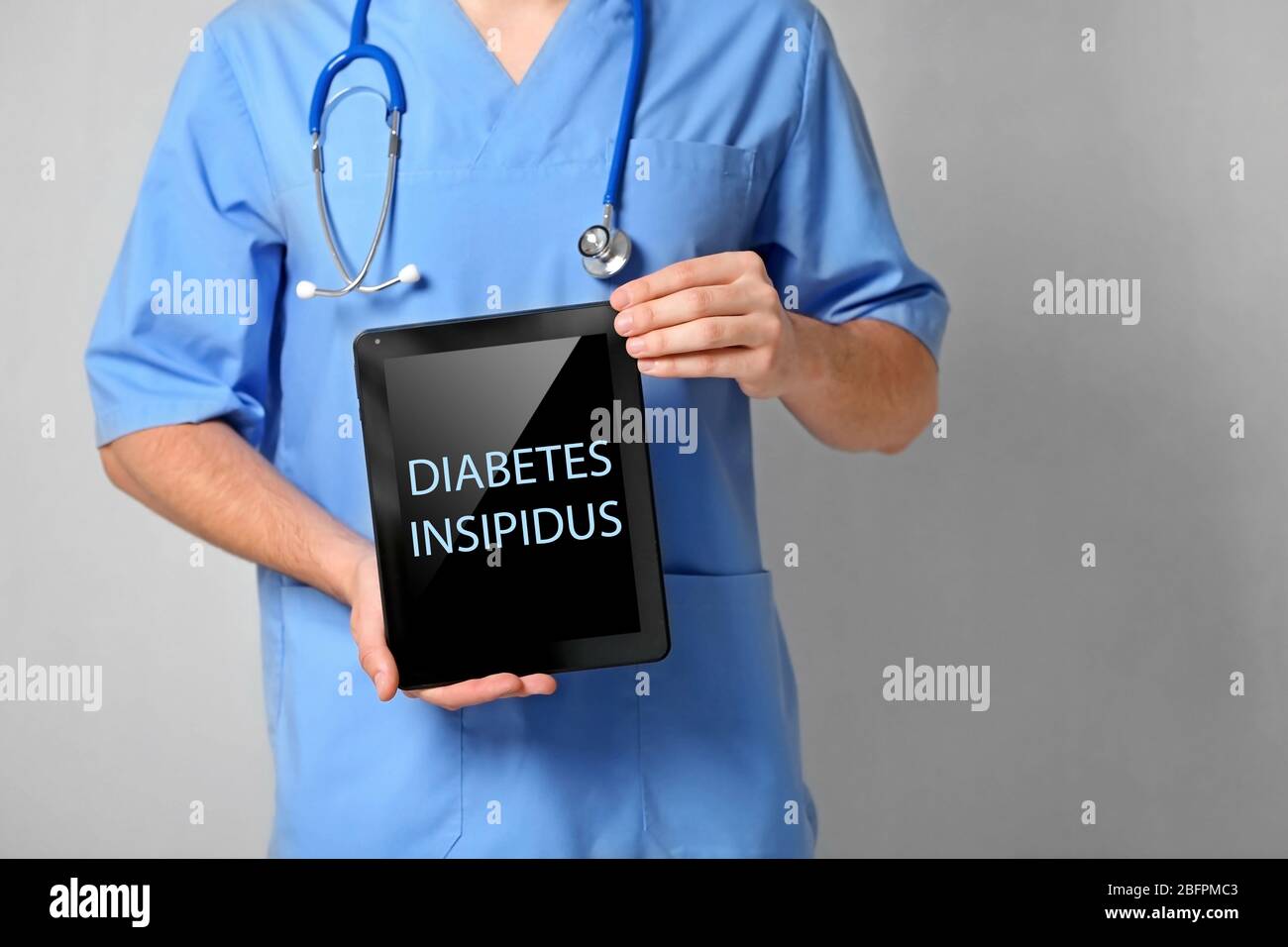 Concept de soins de santé. Médecin tenant un comprimé avec texte DIABÈTE INSIPIDUS sur fond gris Banque D'Images