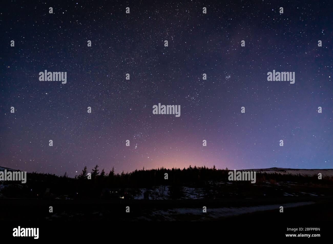 Une colline près du fjord Hvalfjördur dans le sud-ouest de l'Islande à l'heure violette après le coucher du soleil en hiver avec les étoiles qui sortent Banque D'Images
