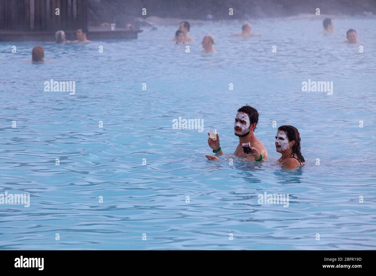 Un couple boit de la bière dans la piscine thermale de Blue Lagoon près de Reykjavik en Islande avec de la vapeur qui s'en lève par temps froid en hiver Banque D'Images