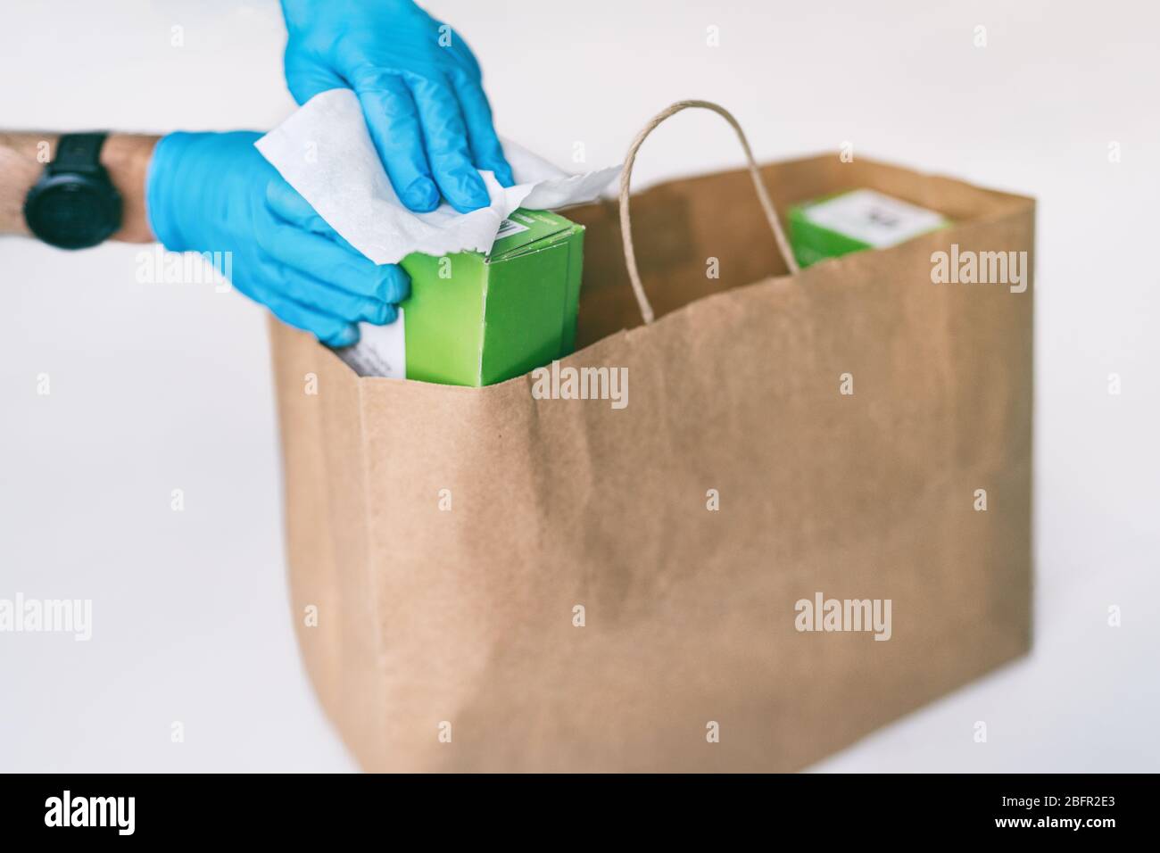 Désinfection de la livraison de nourriture à domicile désinfection des emballages de sacs de shopping en ligne avec des lingettes désinfectantes. Désinfecter les surfaces des emballages avec des gants. COVID-19 hygiène préventive. Banque D'Images