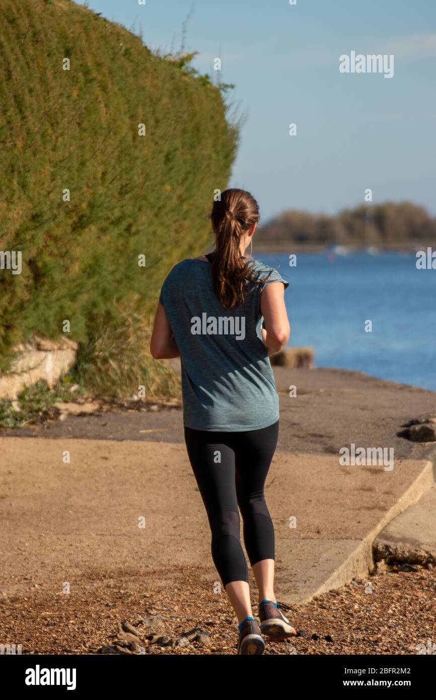 Une jeune femme qui fait du jogging seul le long du rivage Banque D'Images