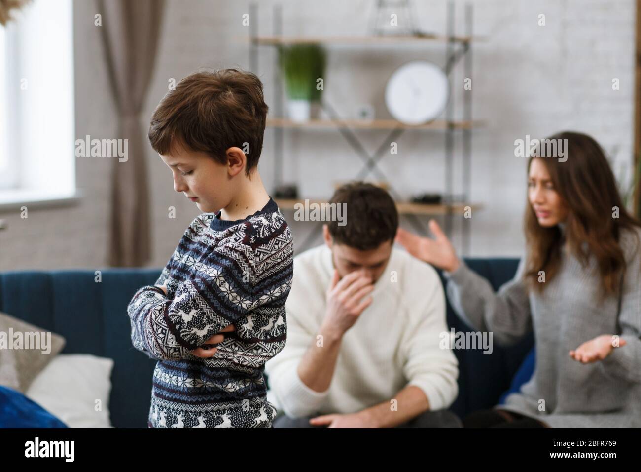 Un petit garçon triste se sent fâché alors que ses parents se battent en arrière-plan. La mère et le père se querelles. Les conflits familiaux et le divorce conduisent aux enfants Banque D'Images