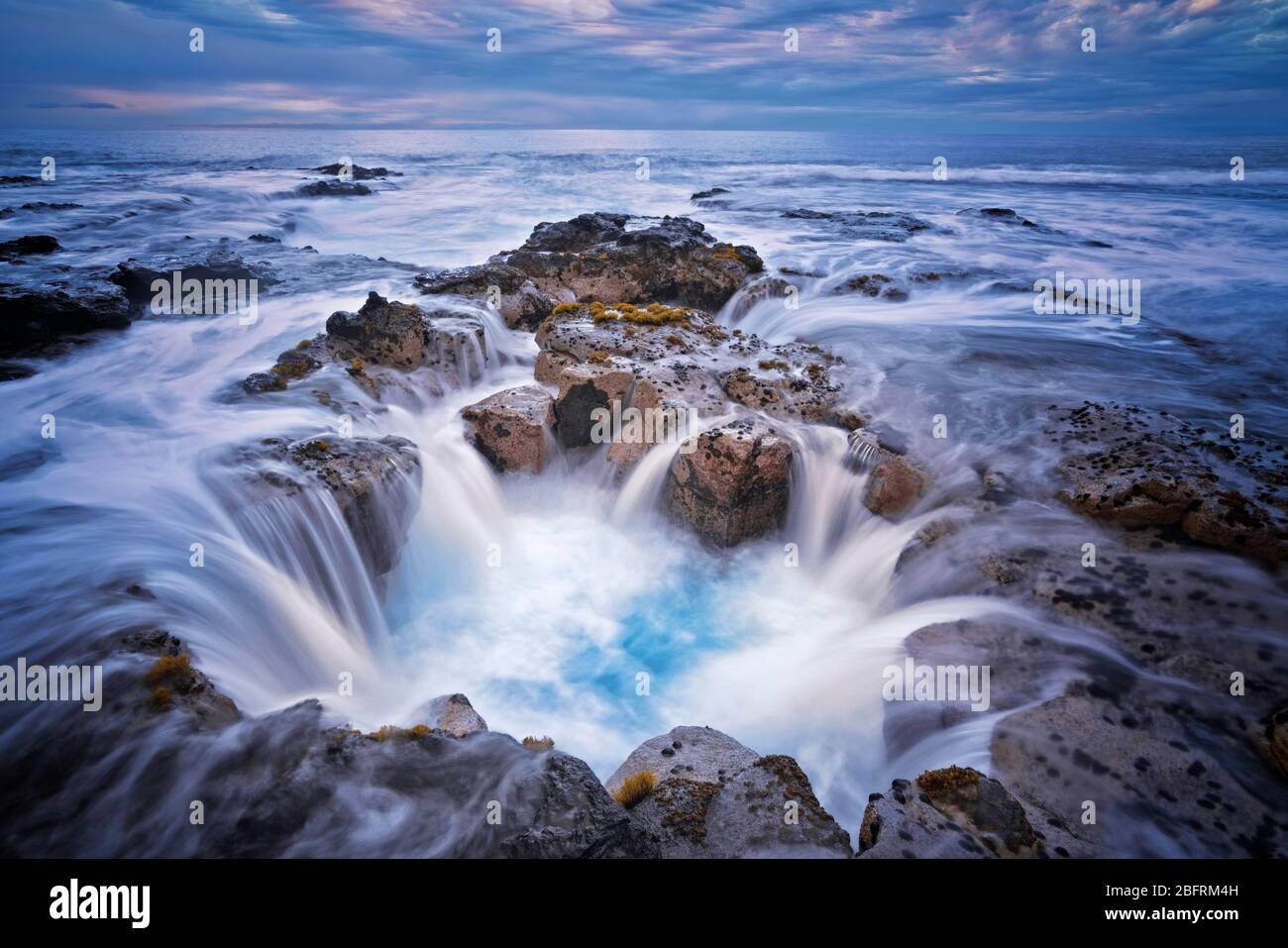 La marée haute se précipite dans le tube de lave connu sous le nom de Pele's well près de Wawaloli Beach sur la Grande île d'Hawaï. Banque D'Images