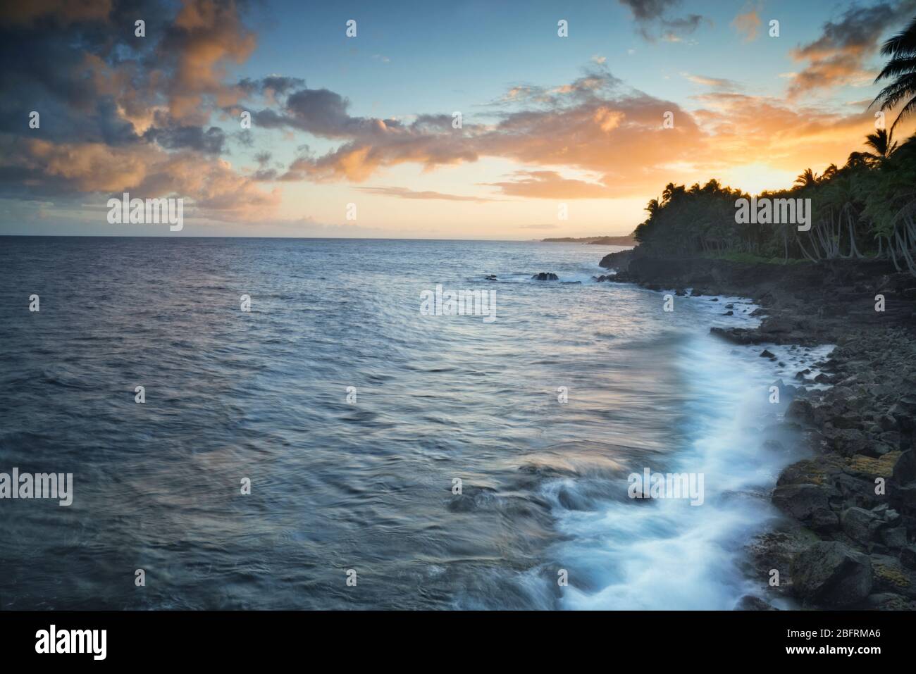 Les vagues du coucher du soleil s'écrasent contre le littoral de lave le long du district de Puna sur la Grande île d'Hawaï. Banque D'Images