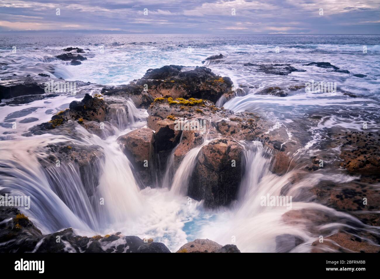 La marée haute du soir se verse dans le tube de lave connu sous le nom de Pele's well près de Wawaloli Beach sur la Big Island d'Hawaï. Banque D'Images