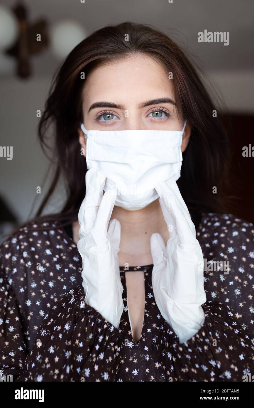 portrait de la jeune femme belle portant un masque blanc en coton et des gants médicaux/chirurgicaux sur fond blanc. Banque D'Images