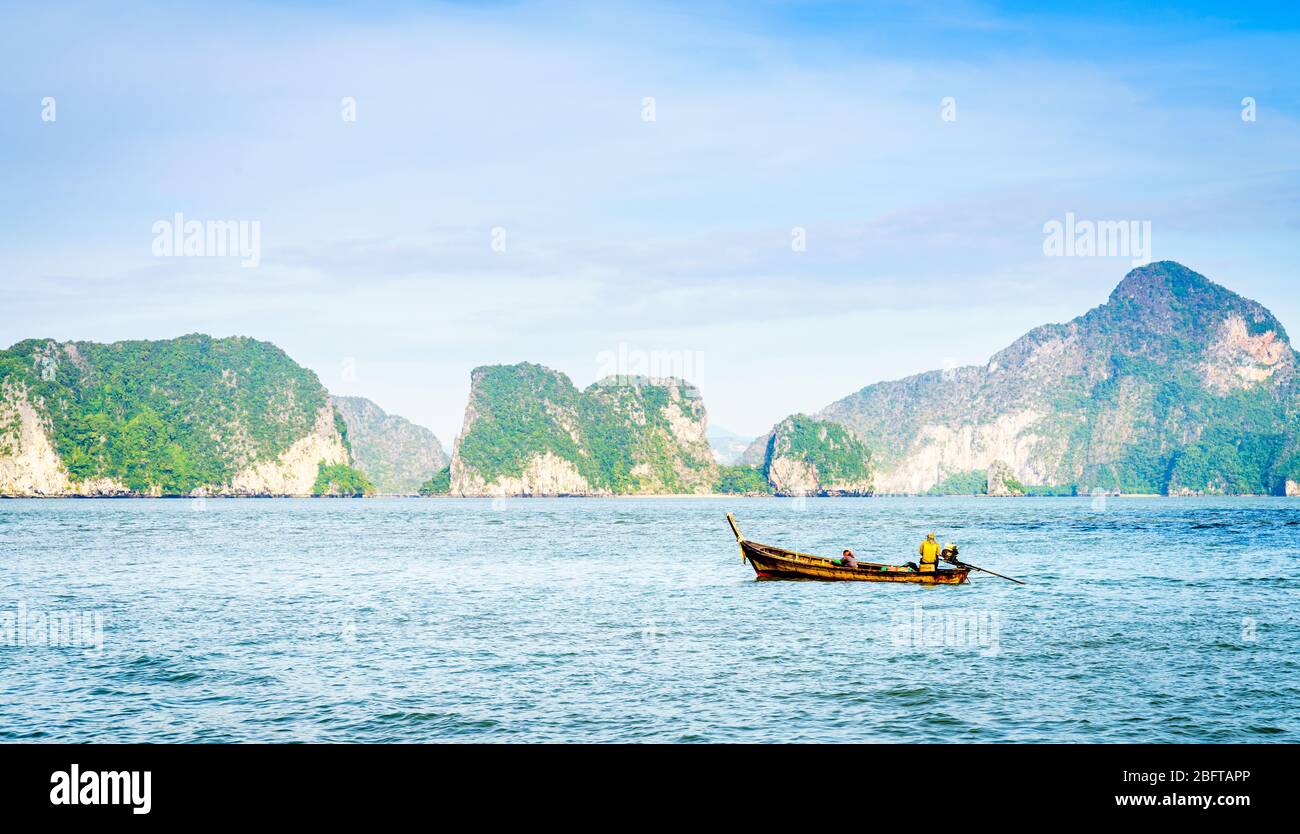 Bateau à moteur thaïlandais traditionnel dans la mer d'Andaman avec le littoral de Phuket en toile de fond Banque D'Images