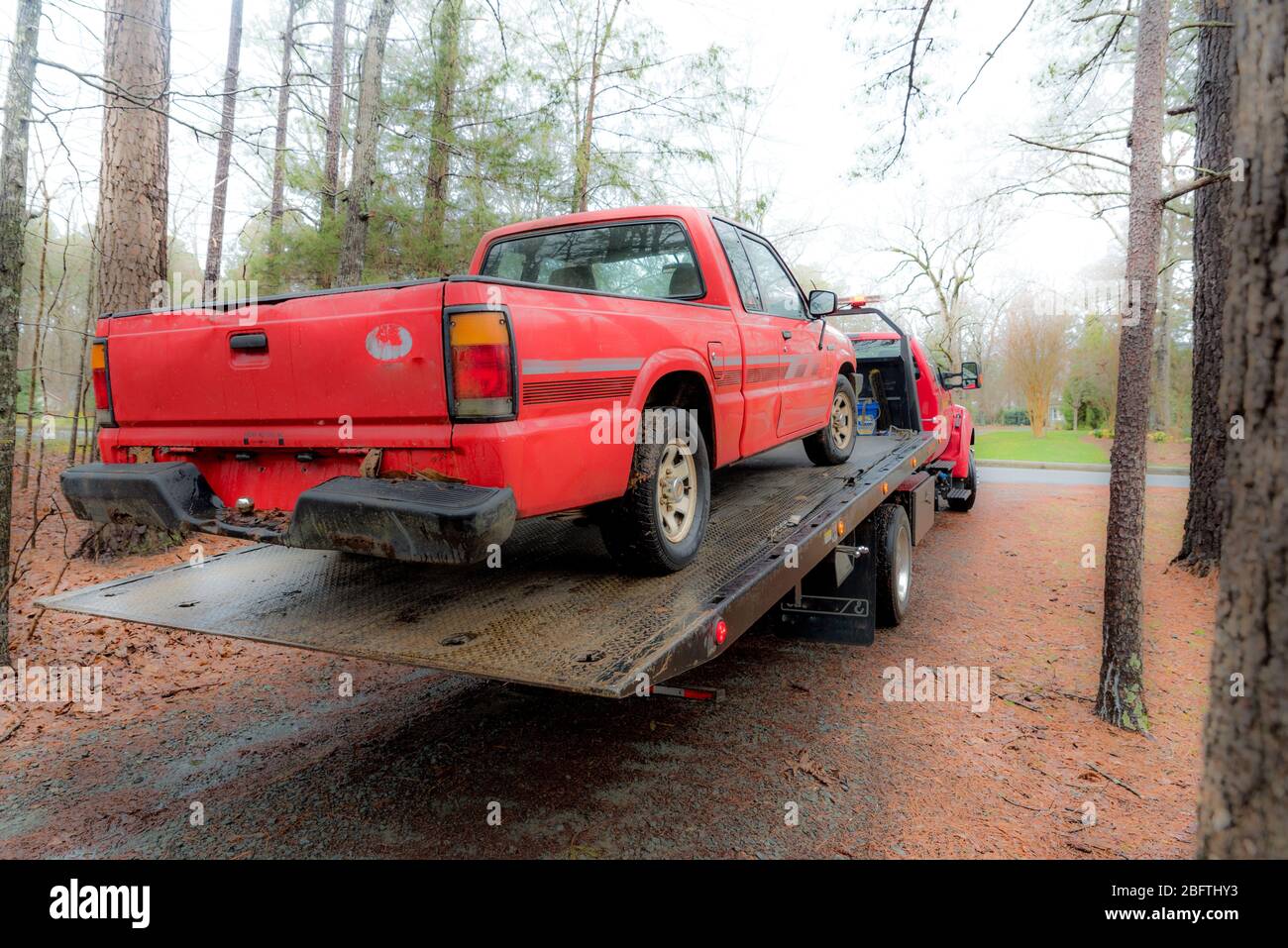 Camion de ramassage rouge chargé sur un camion de remorquage à lit inclinable rouge à transporter le jour de l'hiver en Caroline du Nord Banque D'Images