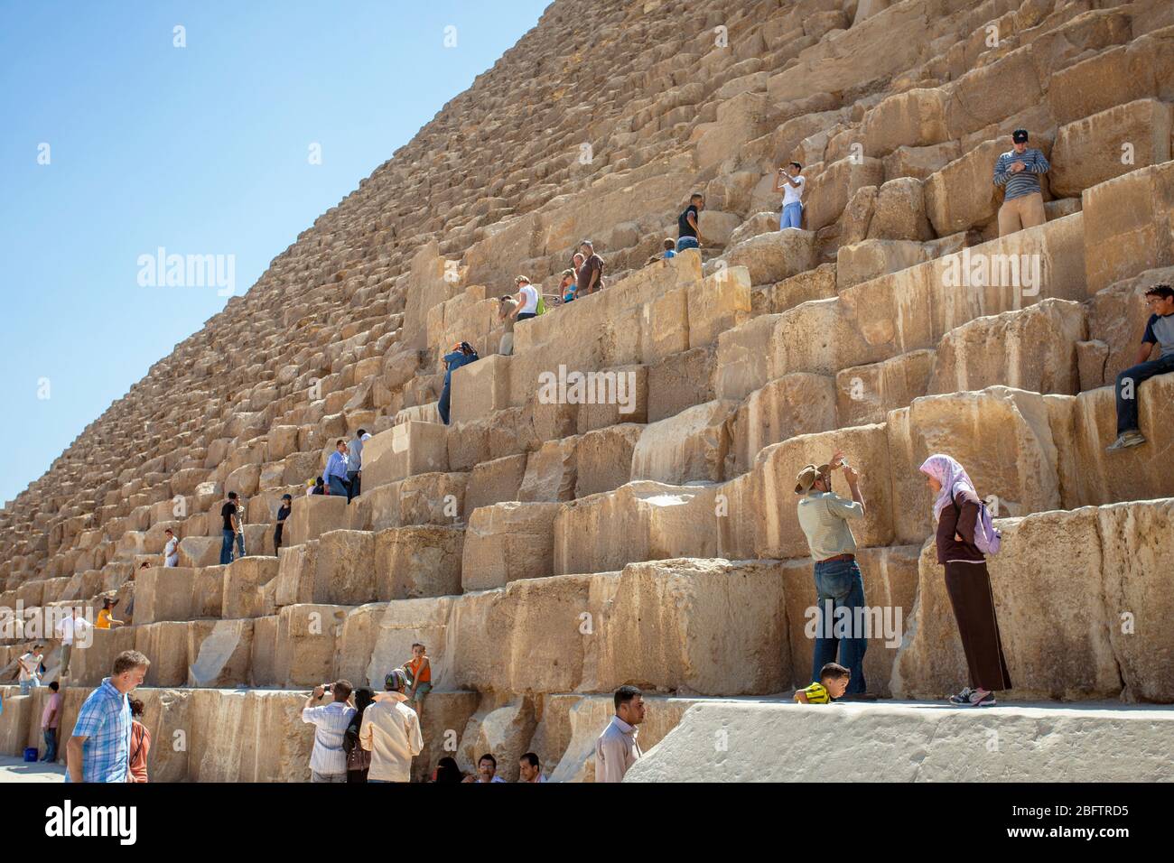 Les touristes grimpent sur la Grande Pyramide de Giza, Egypte. Banque D'Images