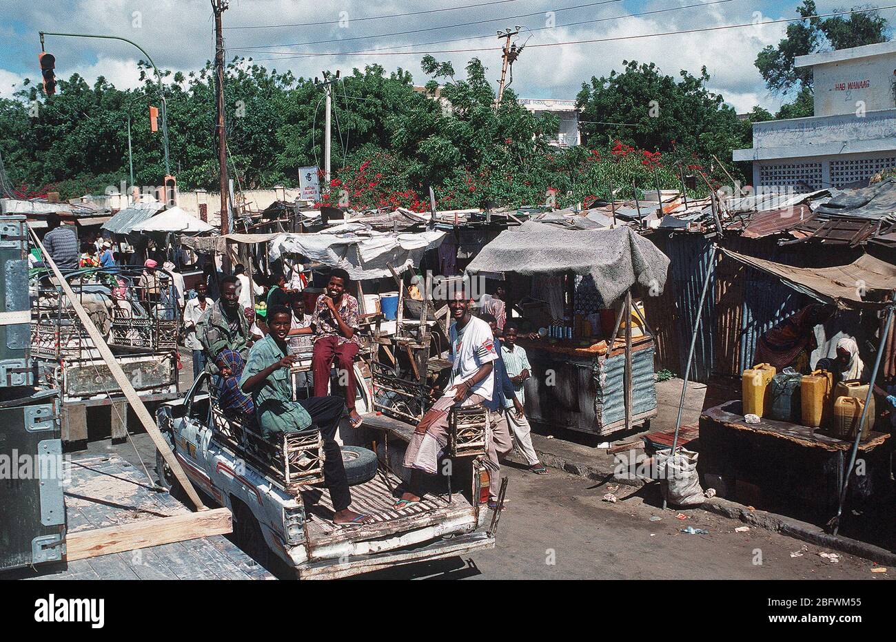 1992 - Un groupe de Somaliens d'hommes, équitation dans un camion, sourire pour la caméra pendant l'effort de secours multinationales l'Opération Restore Hope. Mogadiscio (Somalie) Banque D'Images