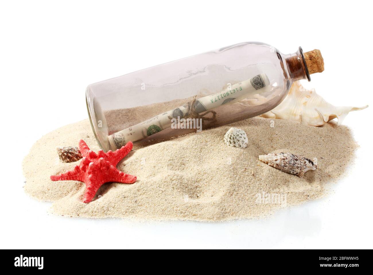 Bouteille de verre avec note à l'intérieur sur sable isolé sur blanc Banque D'Images