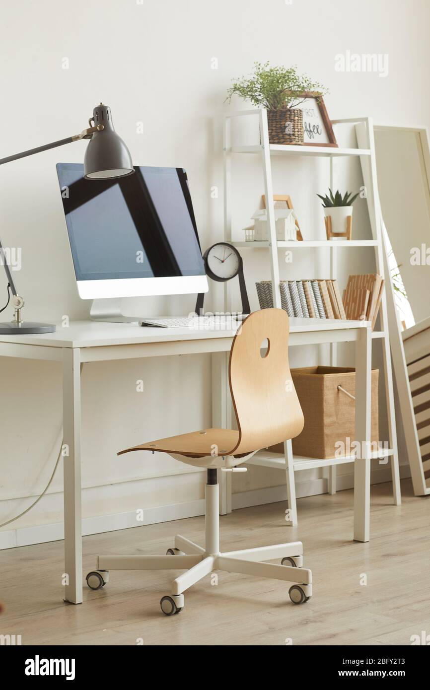 Image verticale de fond de l'espace de travail confortable de bureau à domicile avec un design minimal, foyer sur bois contre bureau d'ordinateur en premier plan, espace de copie Banque D'Images